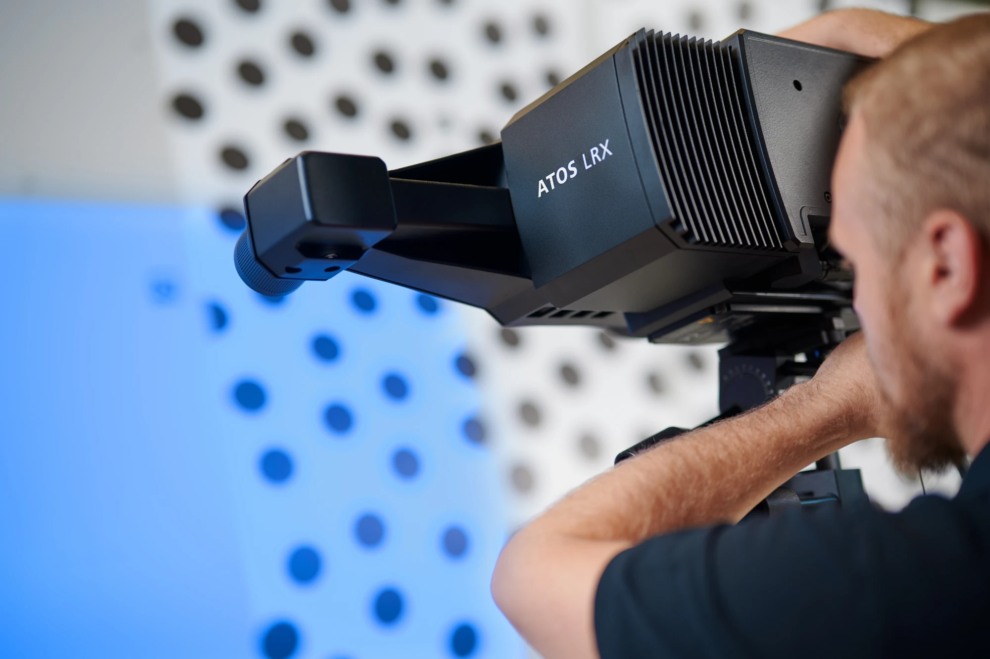 Technician aiming a ZEISS ATOS LRX scanner at a reference panel marked with photogrammetry targets