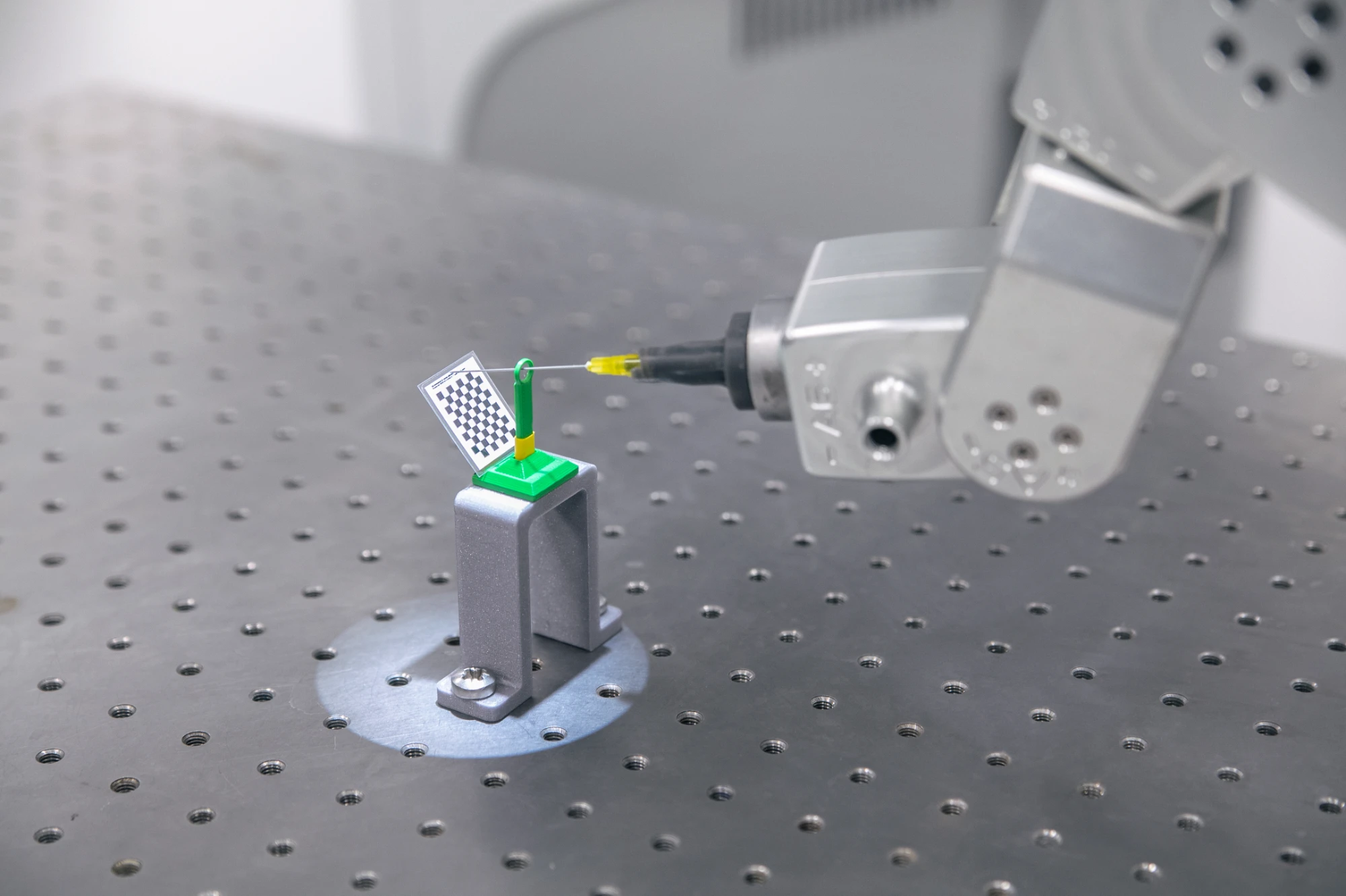 Robotic tactile probe measuring a calibration target mounted on an optical breadboard