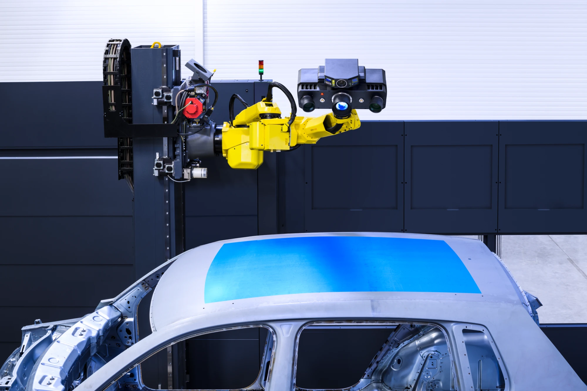 ZEISS ATOS 5X on a yellow robot arm projecting blue measuring light across the roof of a car body-in-white