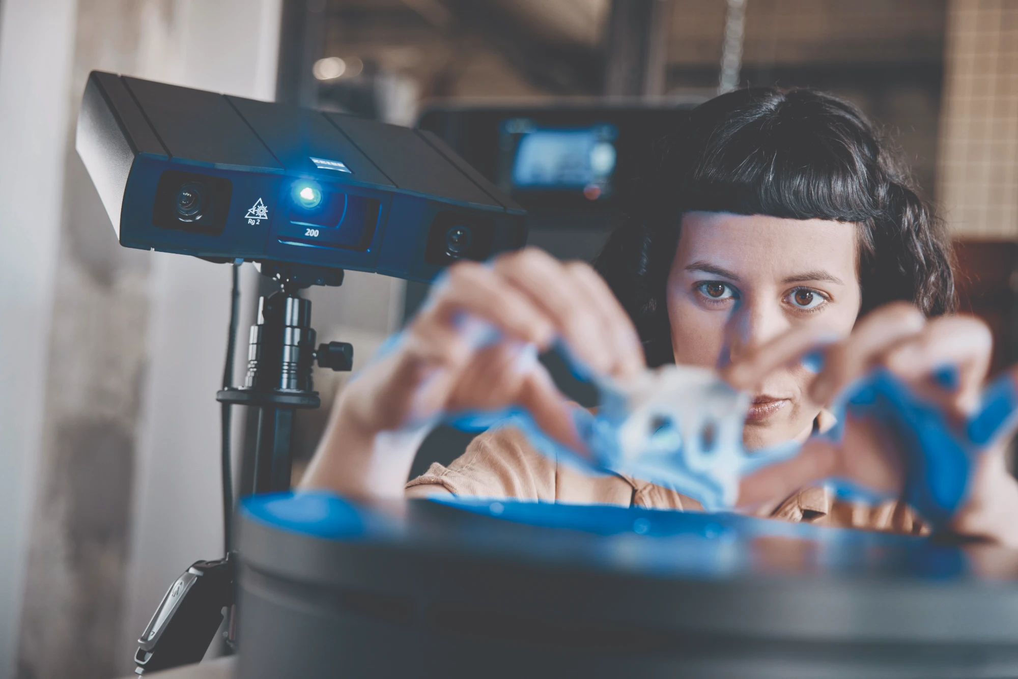 Operator placing a small part on a turntable in front of a GOM Scan 1 projecting blue measuring light