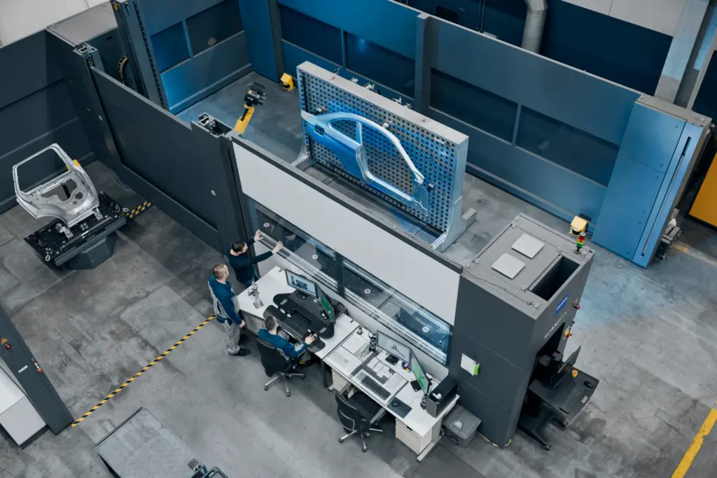 Overhead view of a ZEISS ScanBox cell measuring a body-side panel, with engineers at control desks below