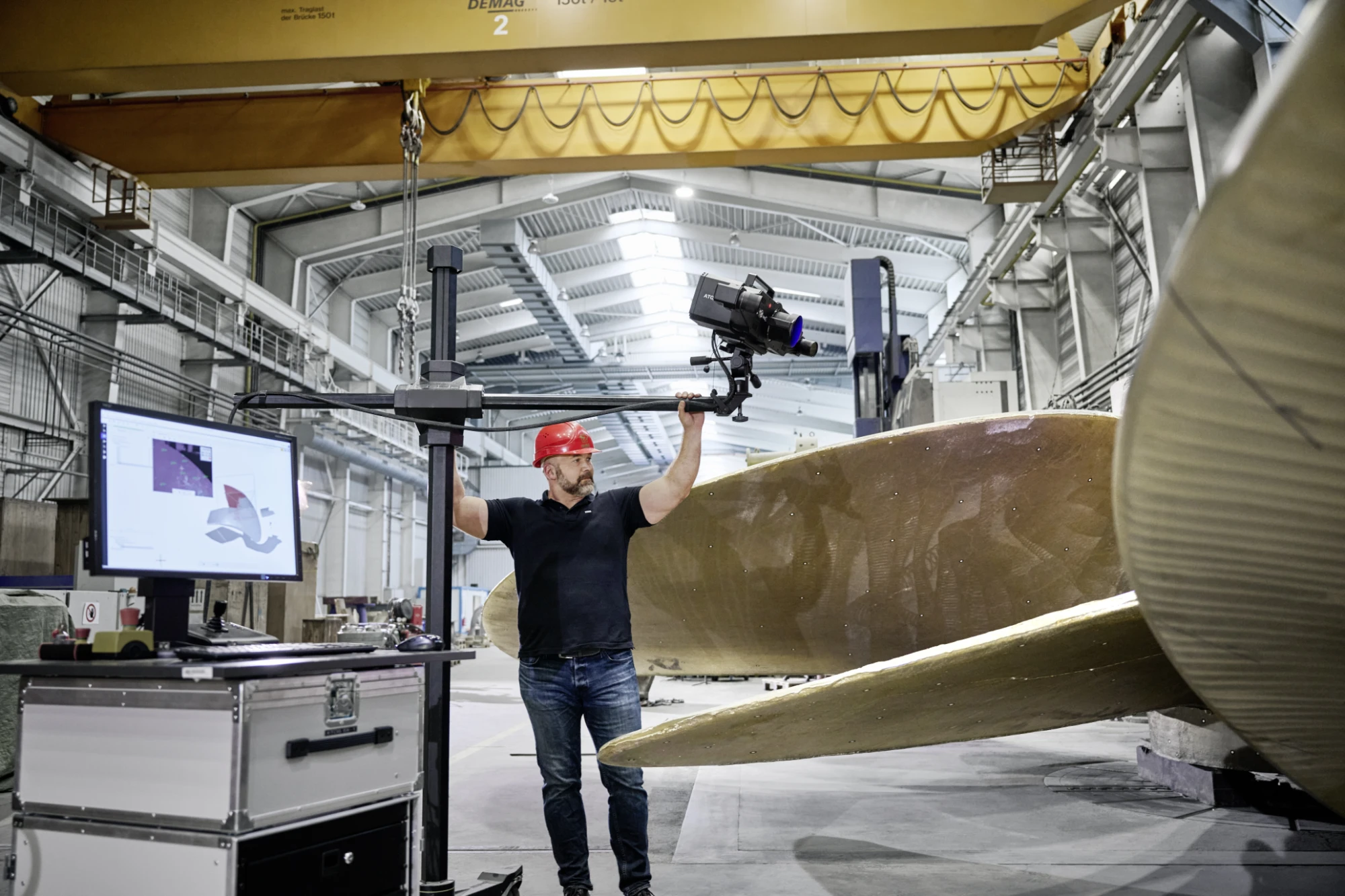 Engineer aiming a tripod-mounted ZEISS ATOS LRX at the bronze blades of a large ship propeller, scan data on the monitor alongside