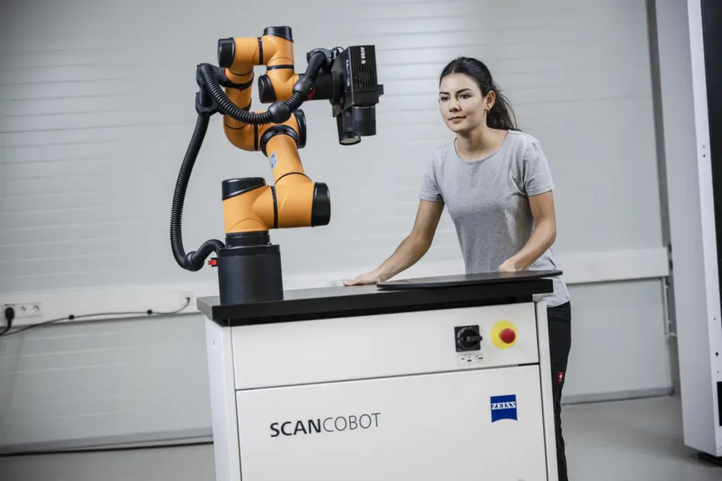 ZEISS ScanCobot: an orange collaborative robot arm carrying a scanner on a wheeled cart, an operator standing alongside