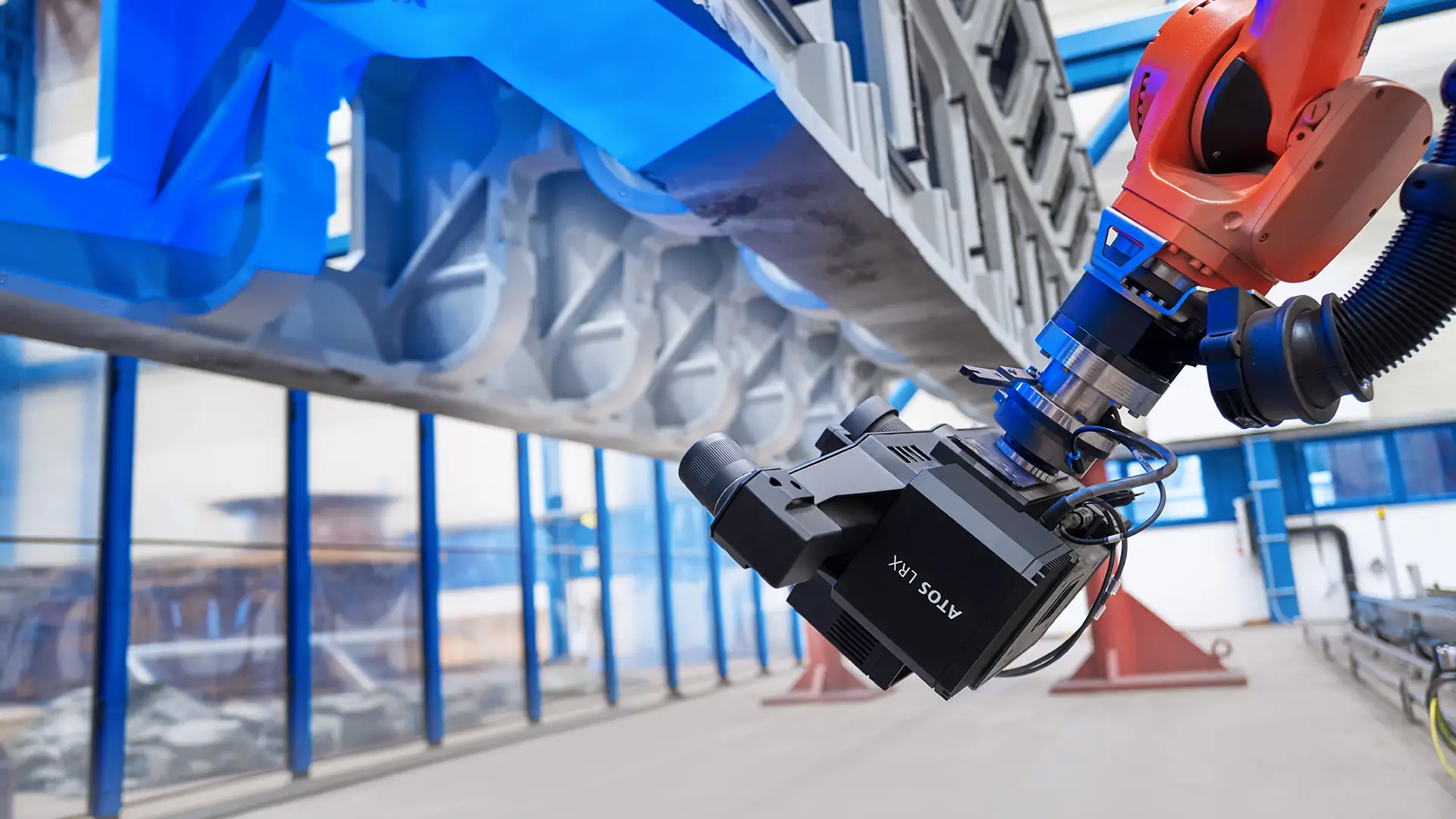ZEISS ATOS LRX on a red robot arm scanning the underside of a large blue cast structure
