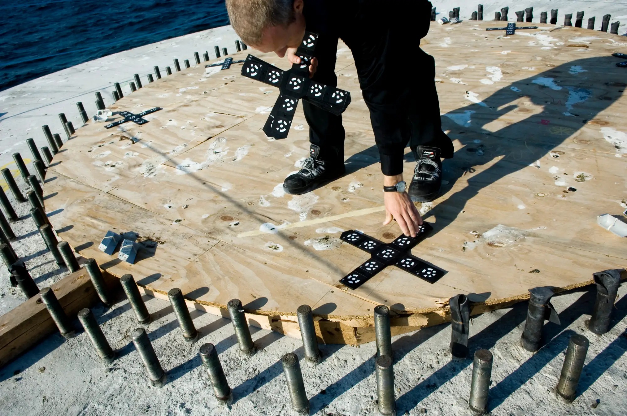 Technician laying photogrammetry reference crosses across the flange of an offshore wind turbine foundation