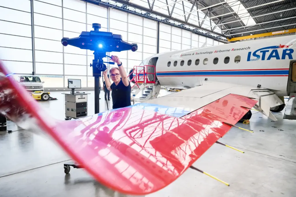 Engineer scanning an aircraft wing with a ZEISS ATOS scanner beside a research jet in a hangar